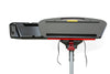 A close-up view of the top part of a TurboDesk lean stool showcasing a textured black shelf with a red underside, a handle, and a slot for tools. The stool is mounted on a silver adjustable pole with a red locking mechanism, set against a white background.