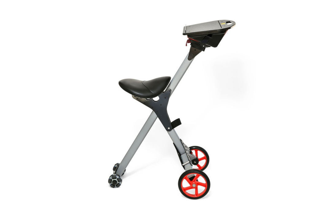 Image of a modern, minimalist walking aid or rollator with a gray frame and bright red wheels. The device features a black seat and a black storage tray on top. It is positioned at an angle, with the handlebars not visible, against a white background.